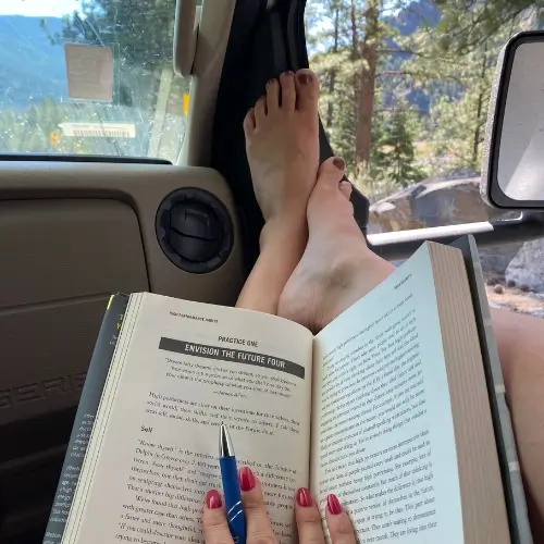 Allie Bjerk with her feet up reading on a road trip