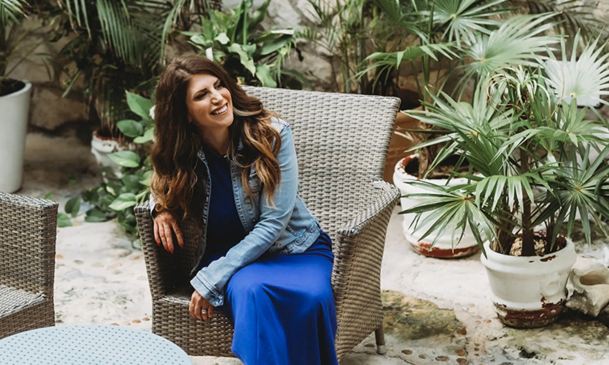 Allie Bjerk seated in a wicker chair among palms