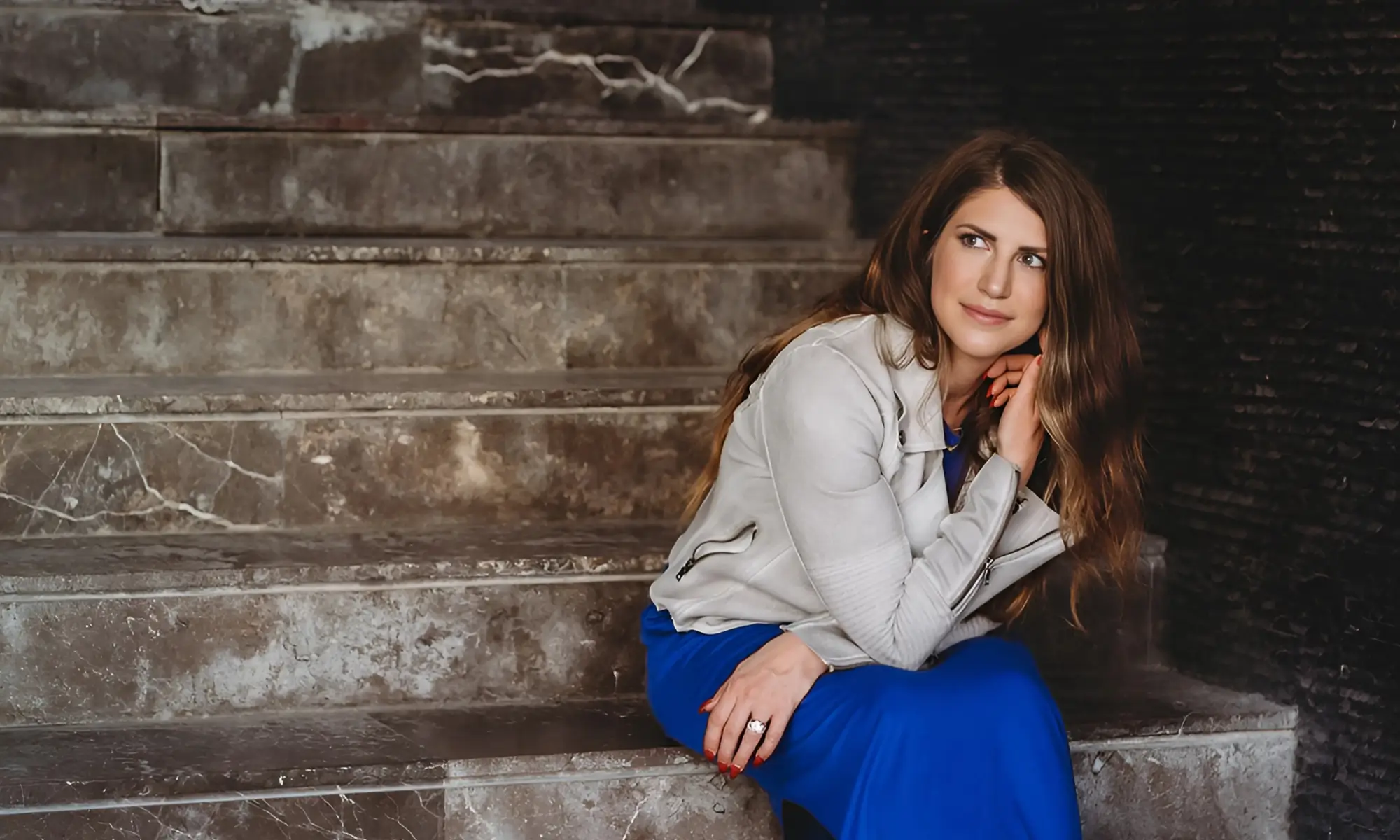 Allie Bjerk in a blue dress on stone steps